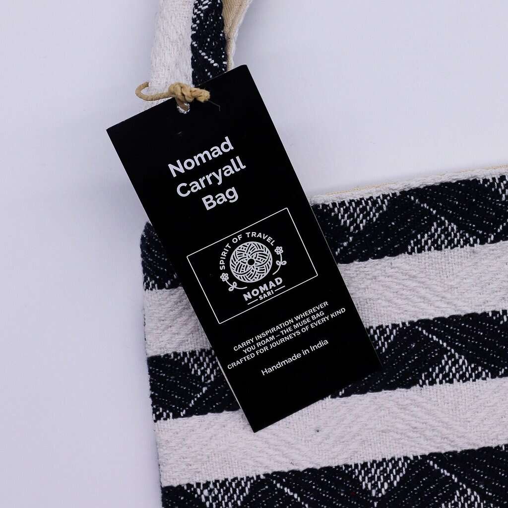 Nomad carryall bag tag on black and white striped fabric.